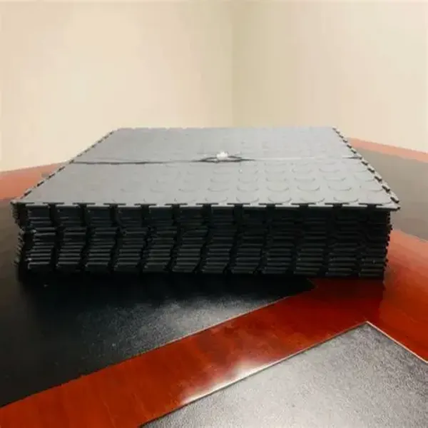 Stack of black interlocking gym flooring tiles in a gym flooring pack