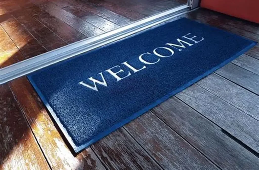 Blue welcome mat at a doorway illustrating The Ultimate Guide to Seasonal Doormats