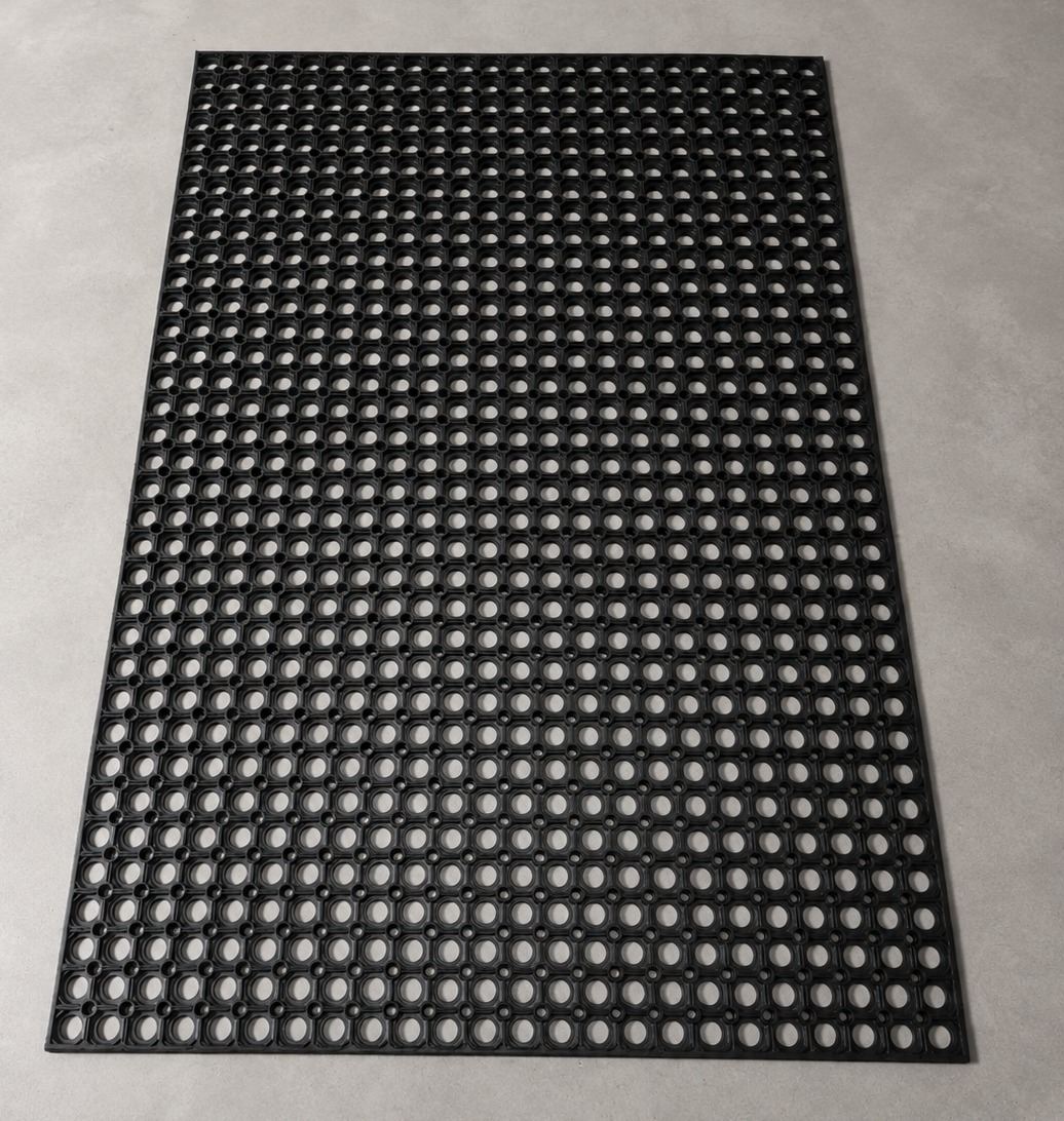 Black workplace safety ring mat for anti-fatigue, drainage and slip-resistant flooring in industrial work areas.